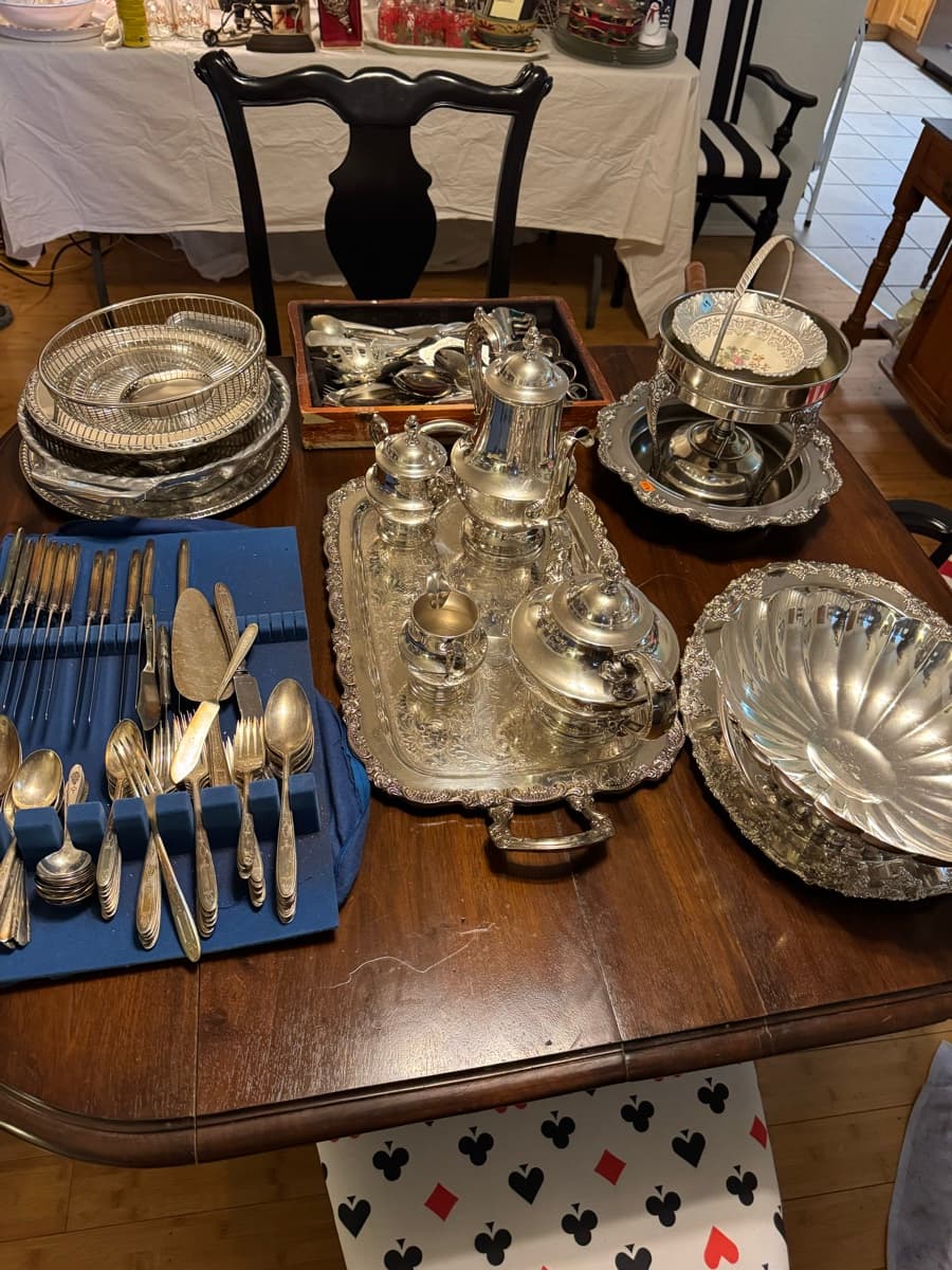 Silver serving pieces, trays, and a tea service laid out on a table