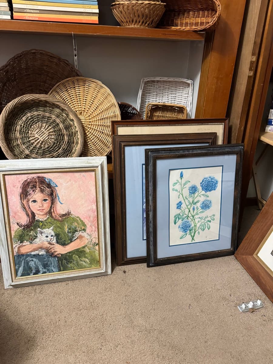 Framed paintings and woven baskets ready for sale at an Oregon estate sale